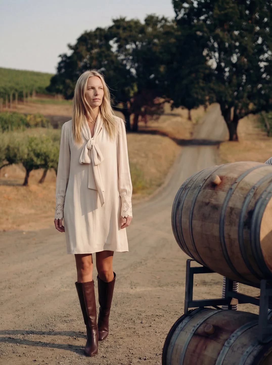 Cartolina: A cream dress beside a vineyard wine barrel.