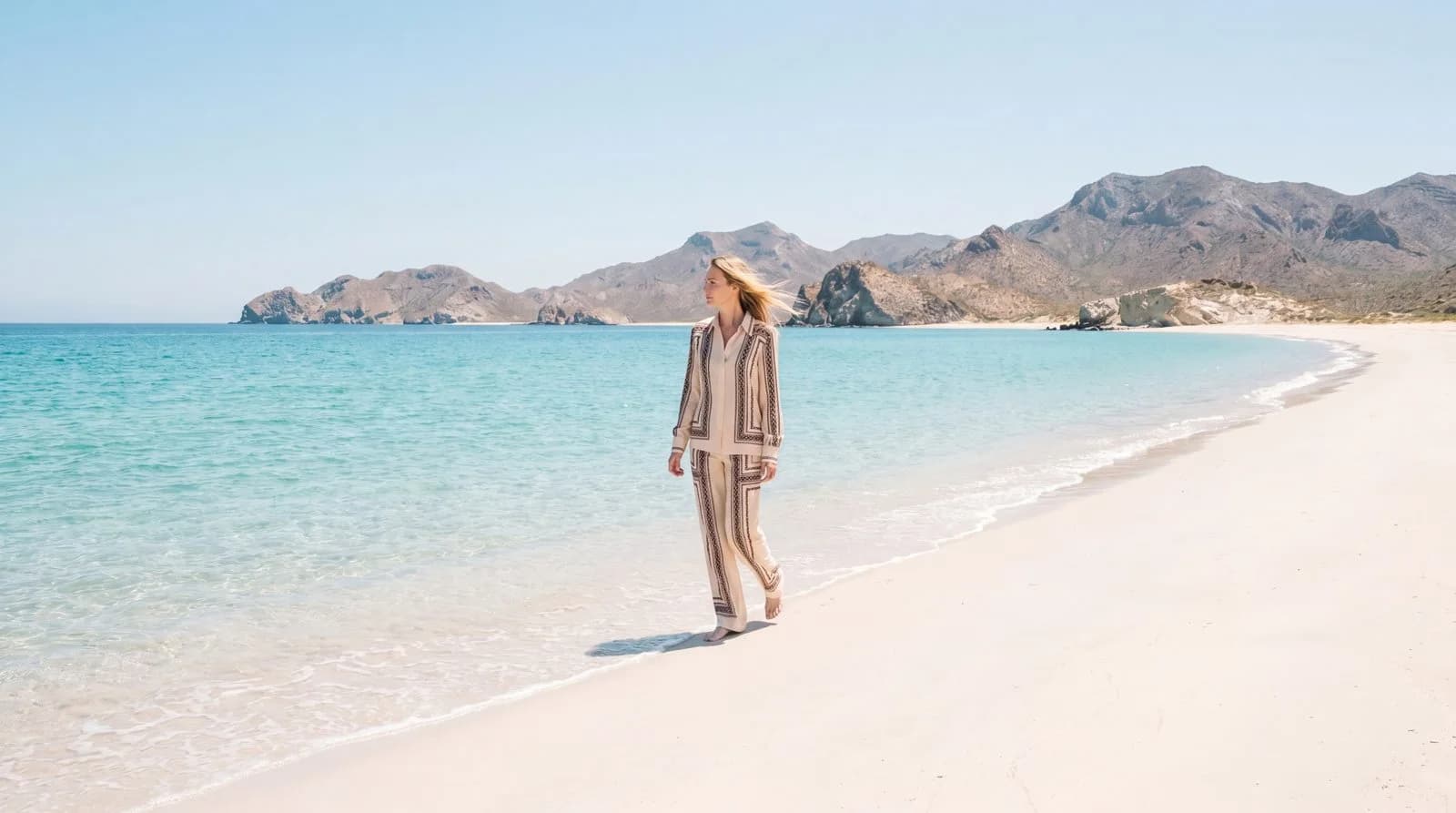 Cartolina: A white trouser look on an open beach.