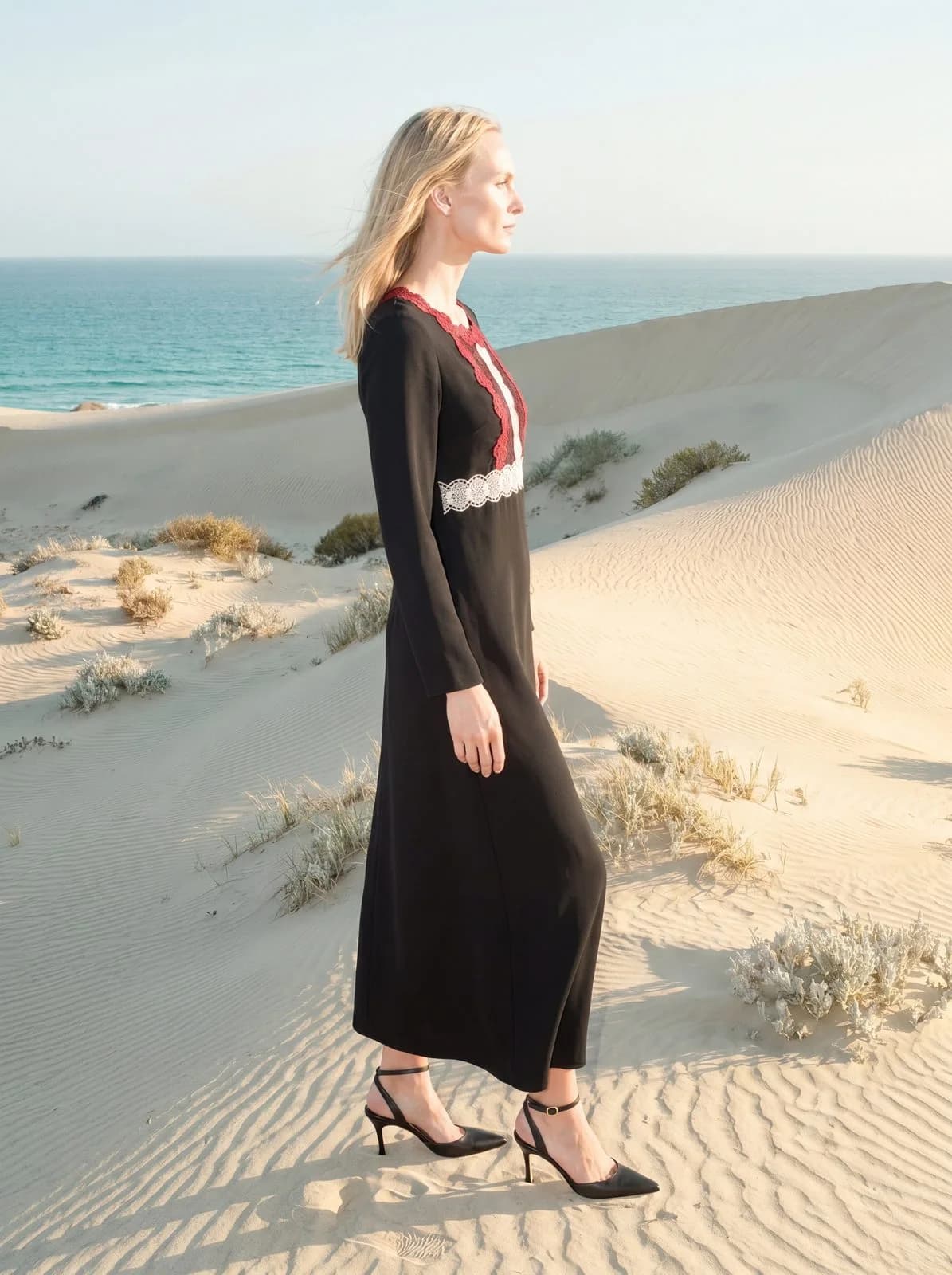 Cartolina: A dark resort dress on a sunlit beach.