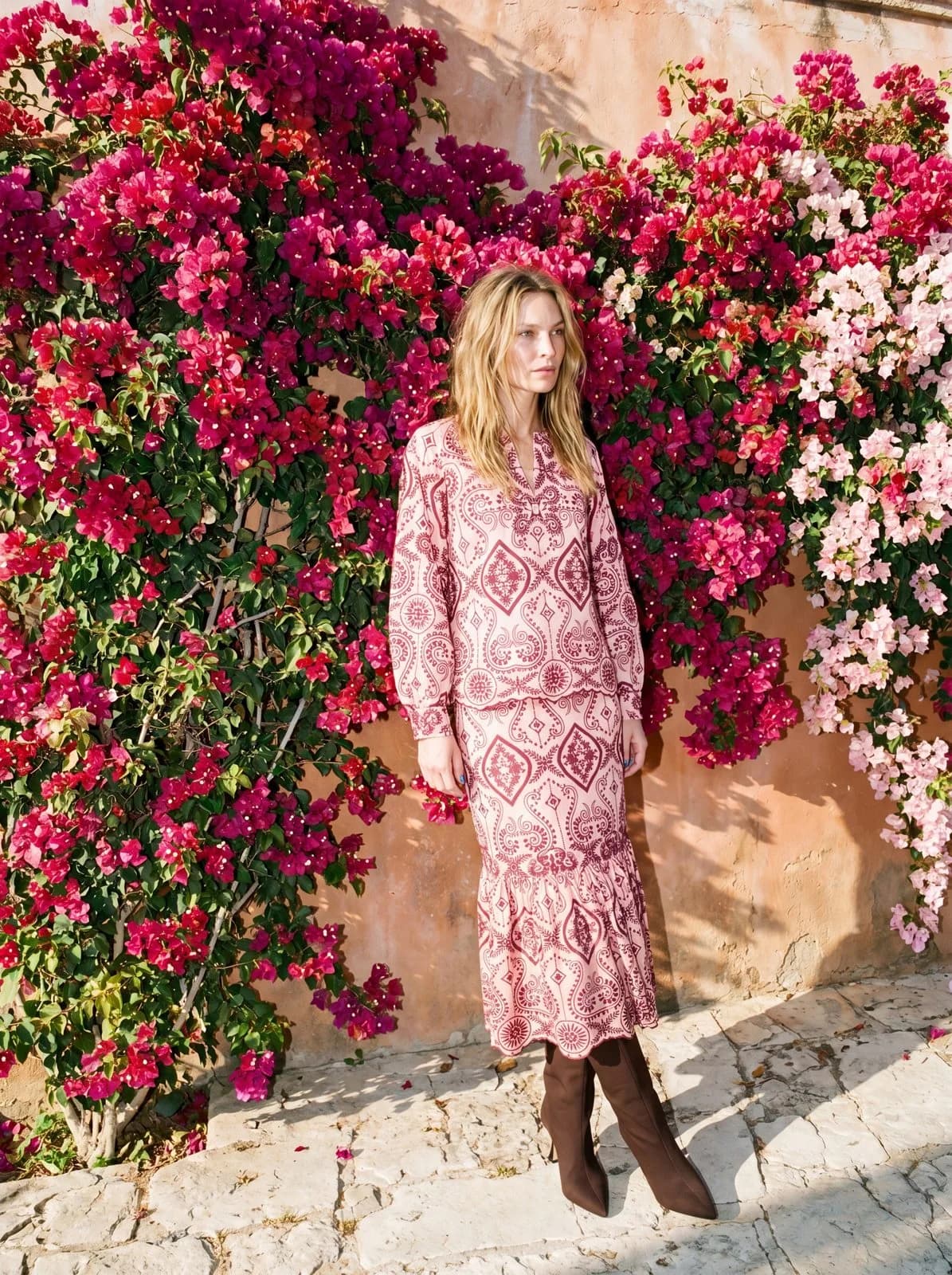 Cartolina: A pink resort dress beneath flowering vines.