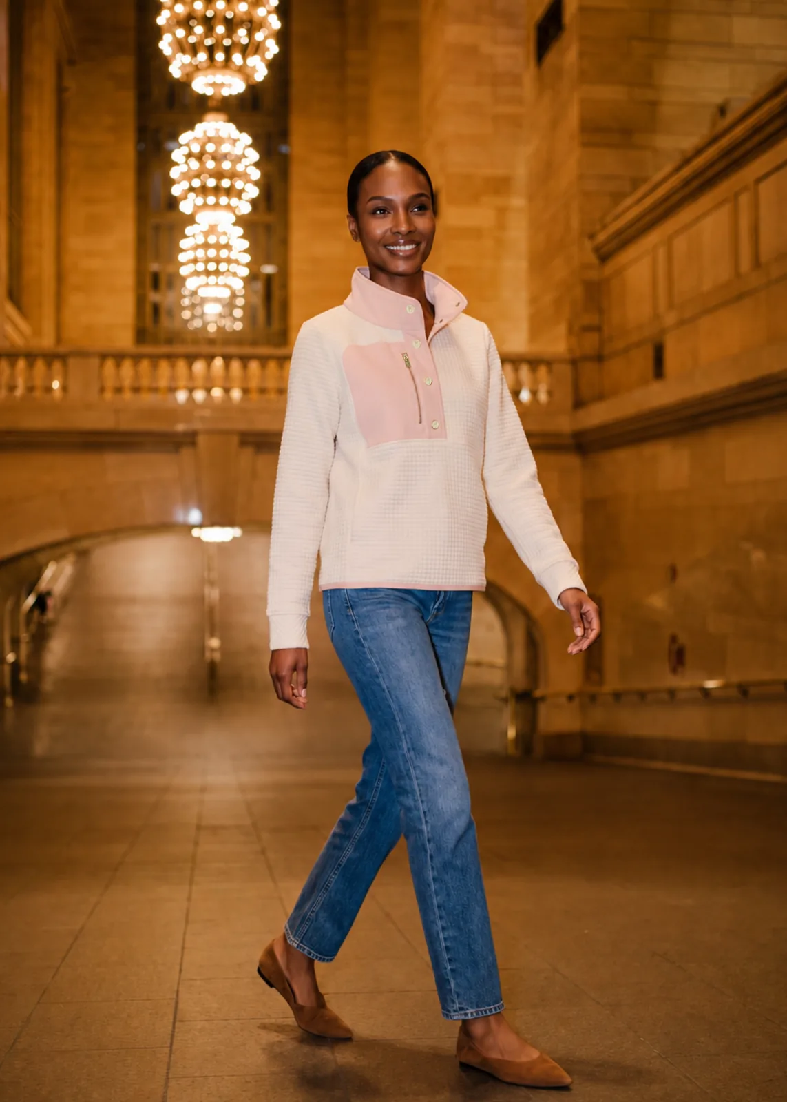 Cherry Lawn Pullover in cream with a model walking through a train terminal.
