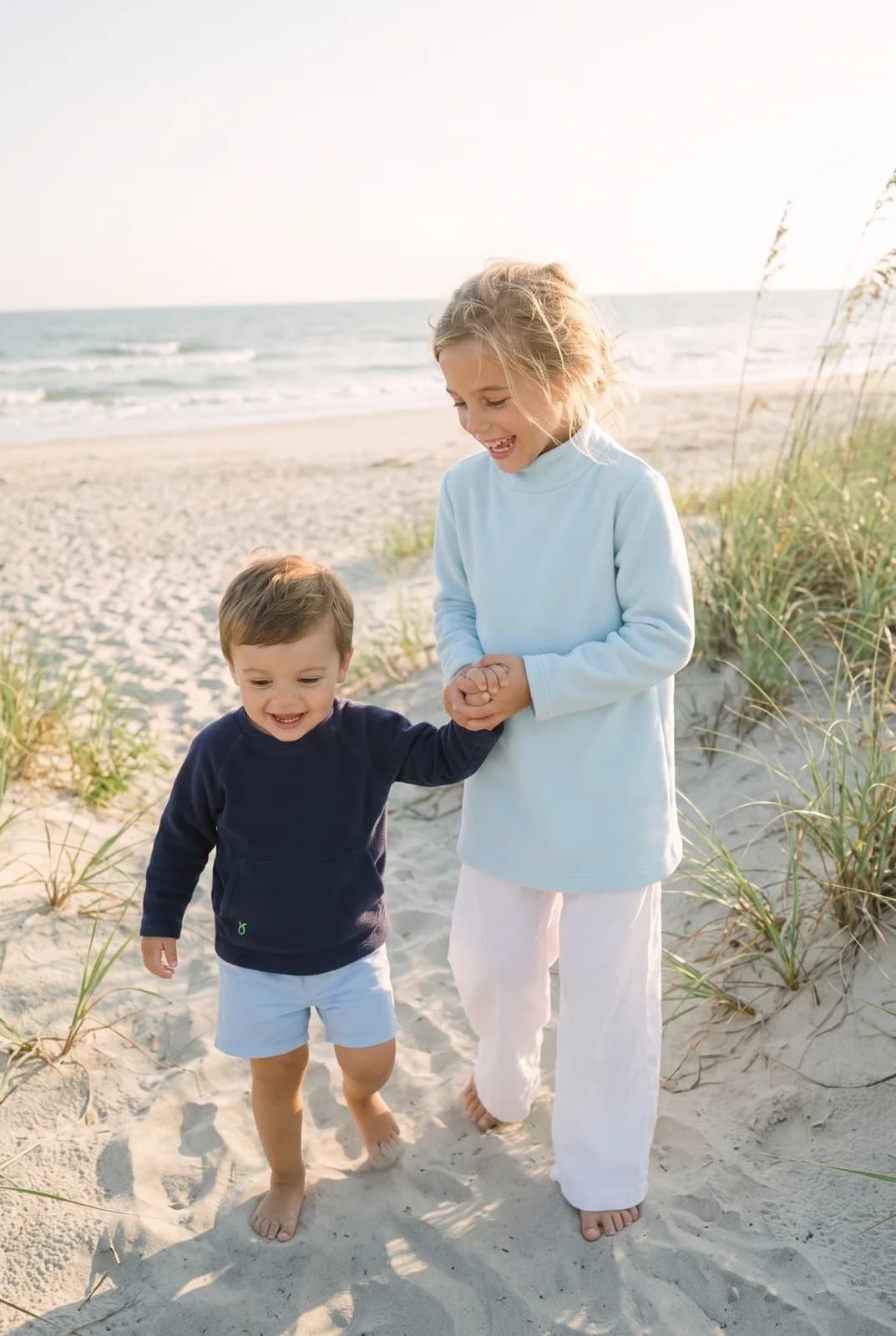 Dudley Stephens: Two children in blue pullovers on a beach.