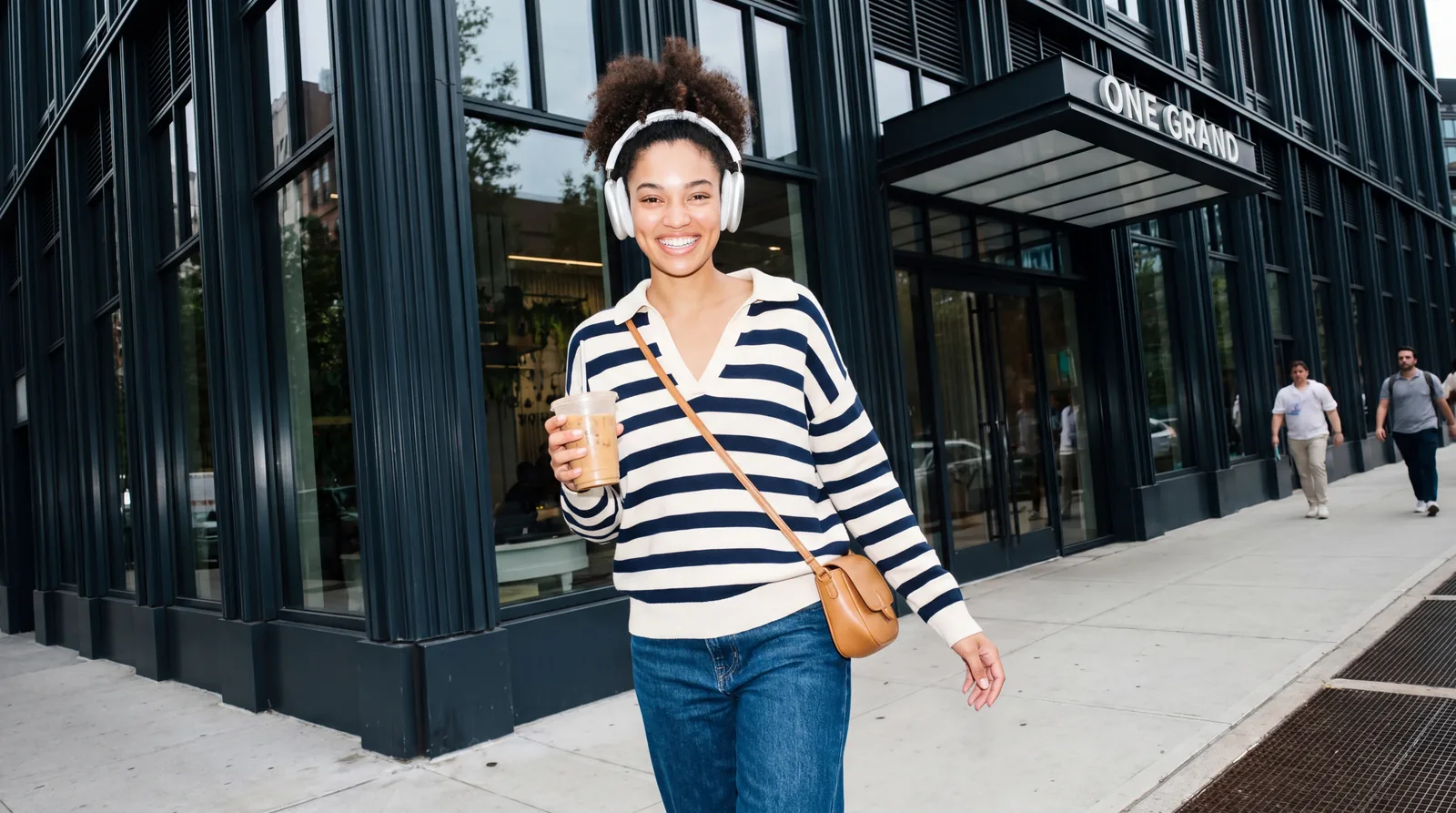 A person carrying a drink walks past the One Grand entrance.