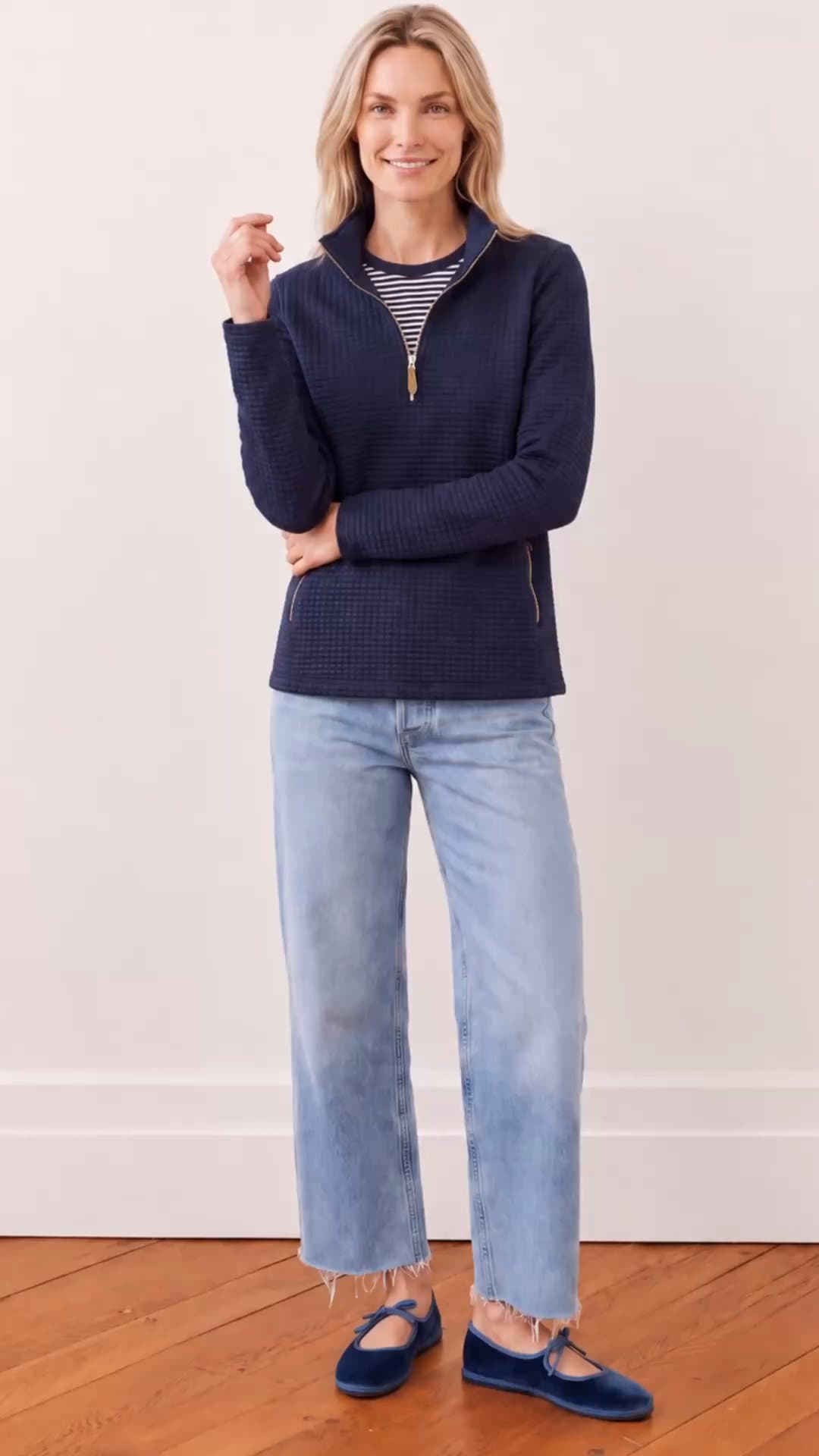 A model in the navy quilted half-zip pullover turns from the front to the back against a white wall, showing the zip, pockets and quilt texture.