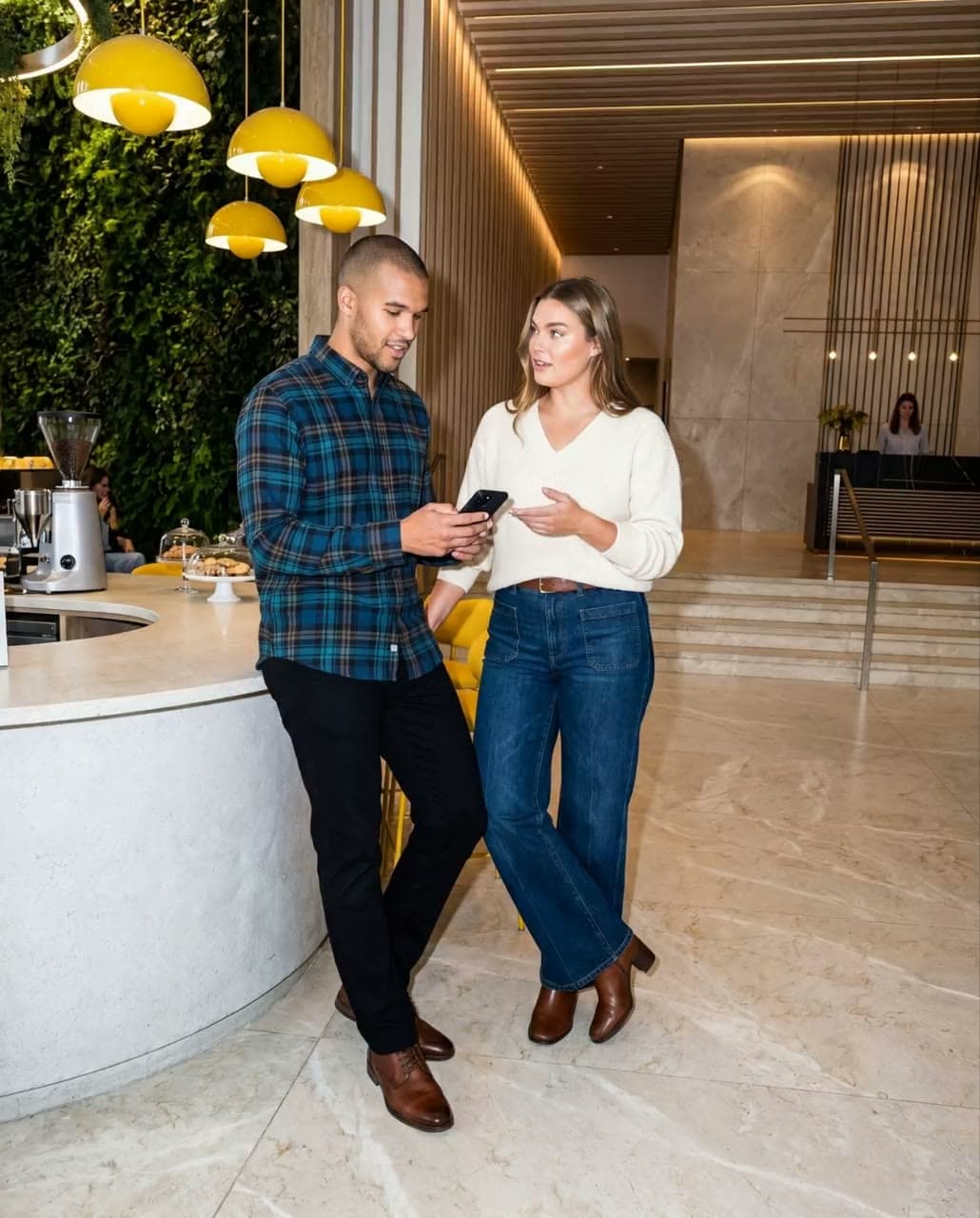 Two people at the lobby cafe counter of the tower, the living green wall moving behind the pendants.