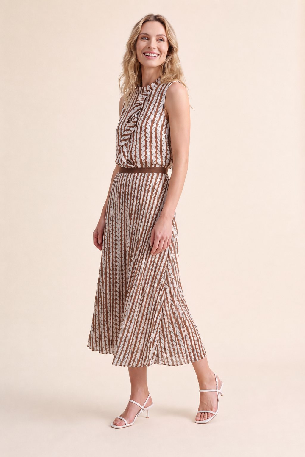 An AI model smiles over her shoulder in the Cartolina Cassie ruffle top and Claudia pleated skirt, both in the thrush print, on a cream studio backdrop.