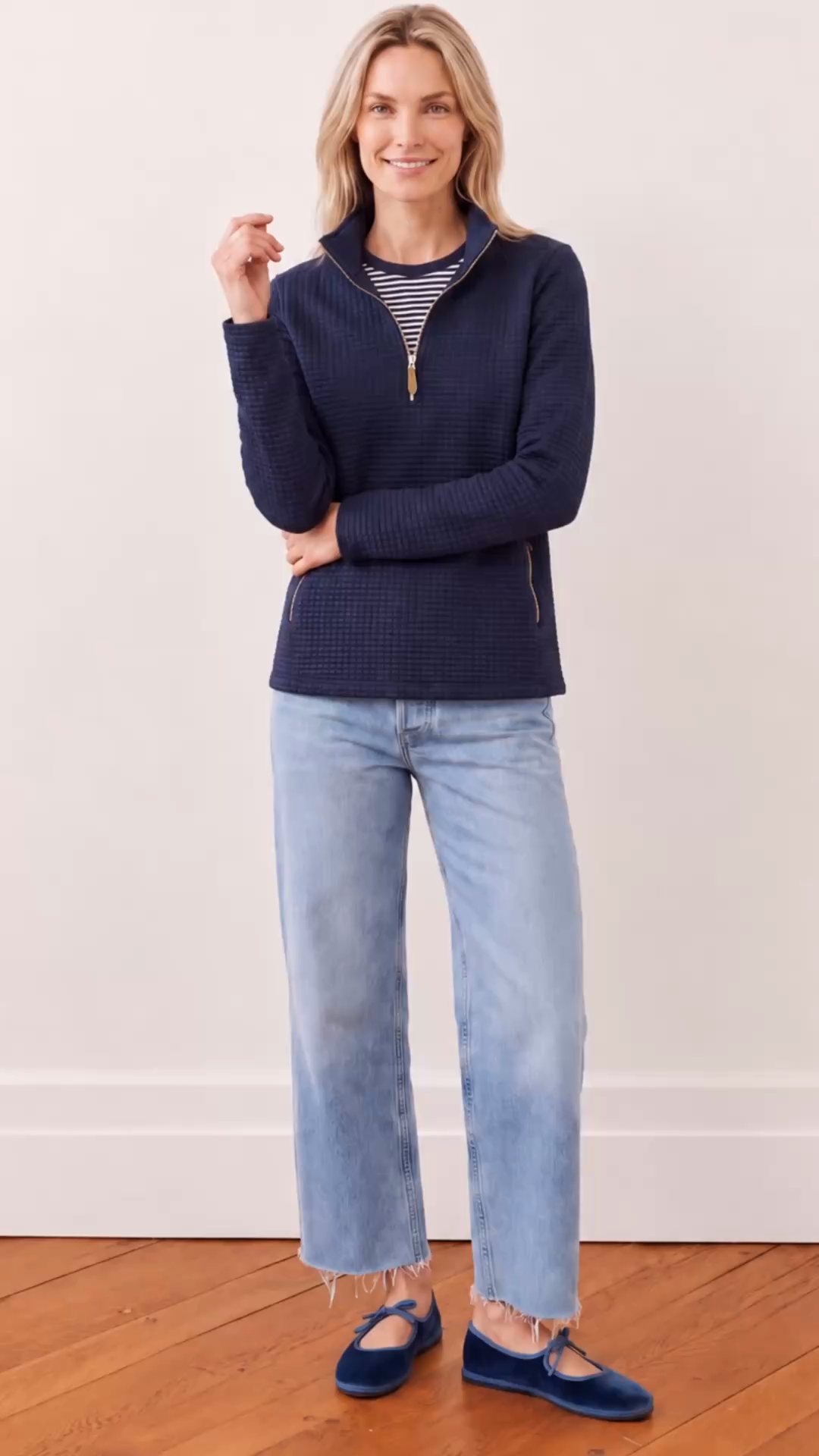 A model in the navy quilted half-zip pullover turns from the front to the back against a white wall, showing the zip, pockets and quilt texture.
